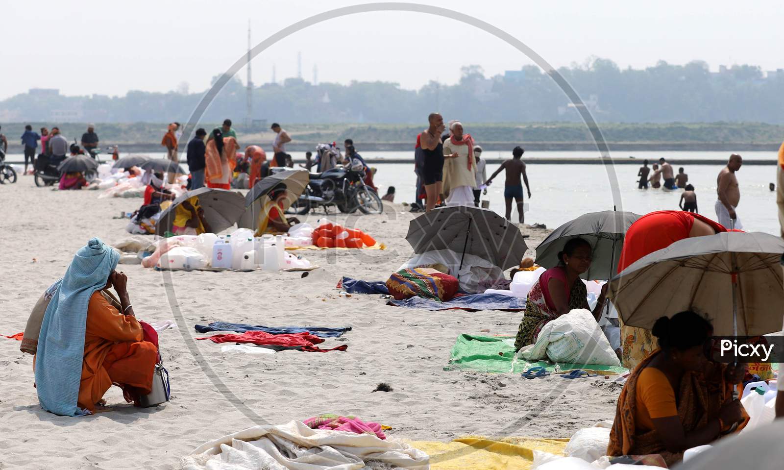 Women Taking Shelter Under Umbrellas on a Hot Day At The Bank Of Ganga River in Prayagraj on May 30,2020