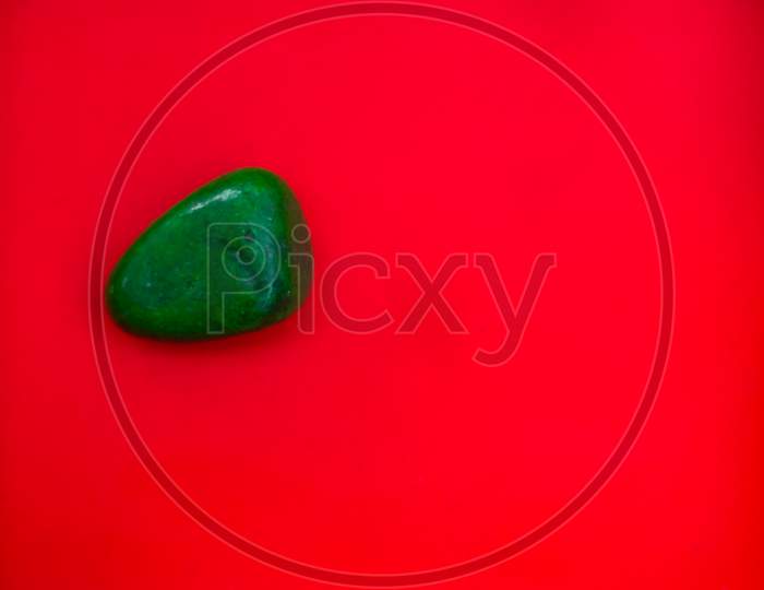 Green Color Natural Pebbles Isolated On Red Background With Space For Copy Text And Words. Multi Color Natural Pebbles Stone. Green Color Stone Isolated. Colorful Sea Stones.