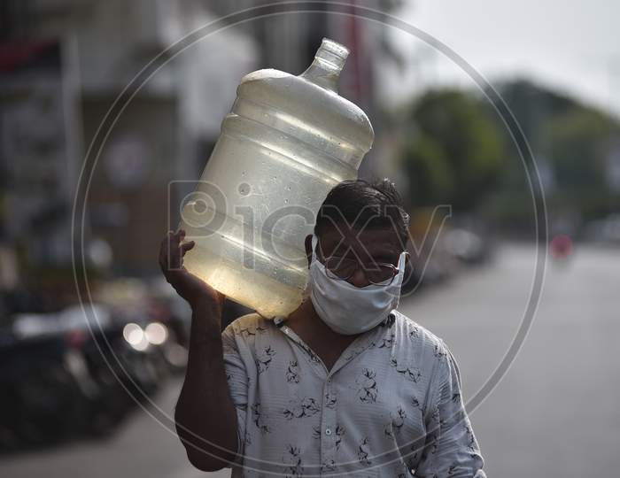 A Man with a protective face mask Carries Water Can Over His Shoulder On A Hot Summer Day, During The Ongoing Coronavirus Lockdown, In Vijayawada.
