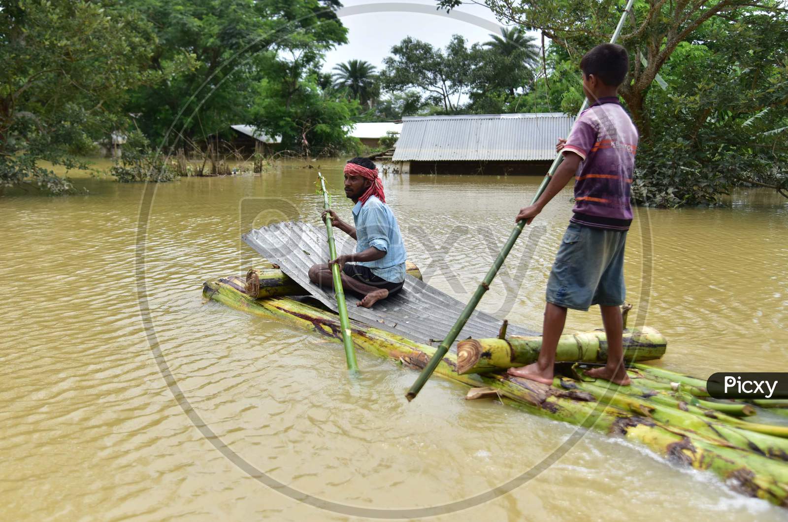Villagers Row A Makeshift Raft Past partially Submerged Houses At A Flood-Affected Village In Hojai District Of Assam On May 30,2020.