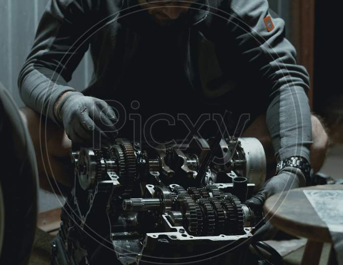 Man repairing his motorcycle engine in the garage.