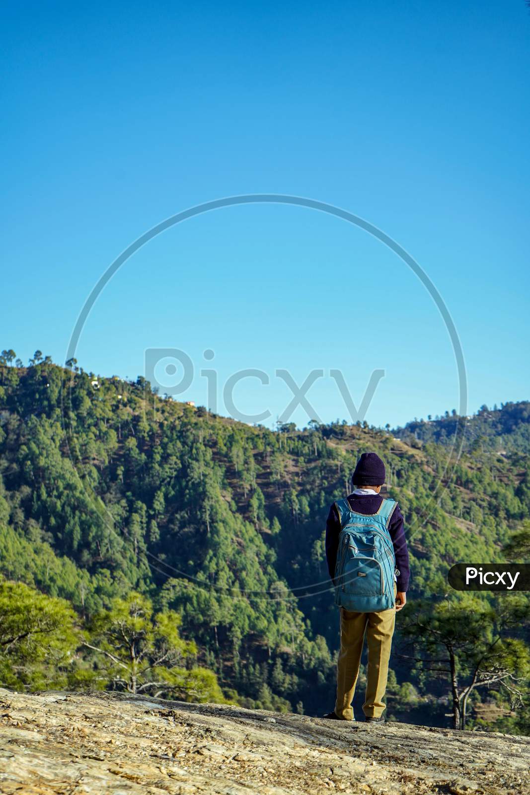 Almora, Uttrakhand / India- May 30 2020 : A School Boy Standing On The Cliff Of A Mountain With Beautiful Blue Sky Overhead.