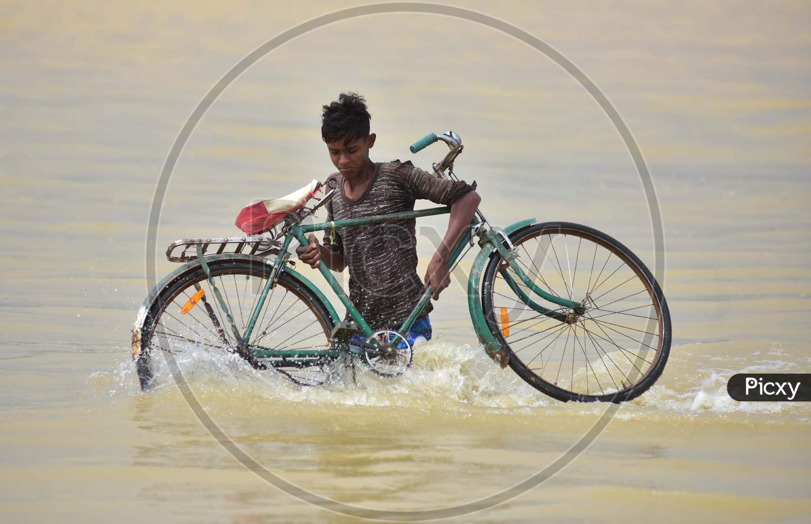 A Villager Carries His Bicycle As He Wades Through A Flooded Road In Hojai District Of Assam On May 30,2020.