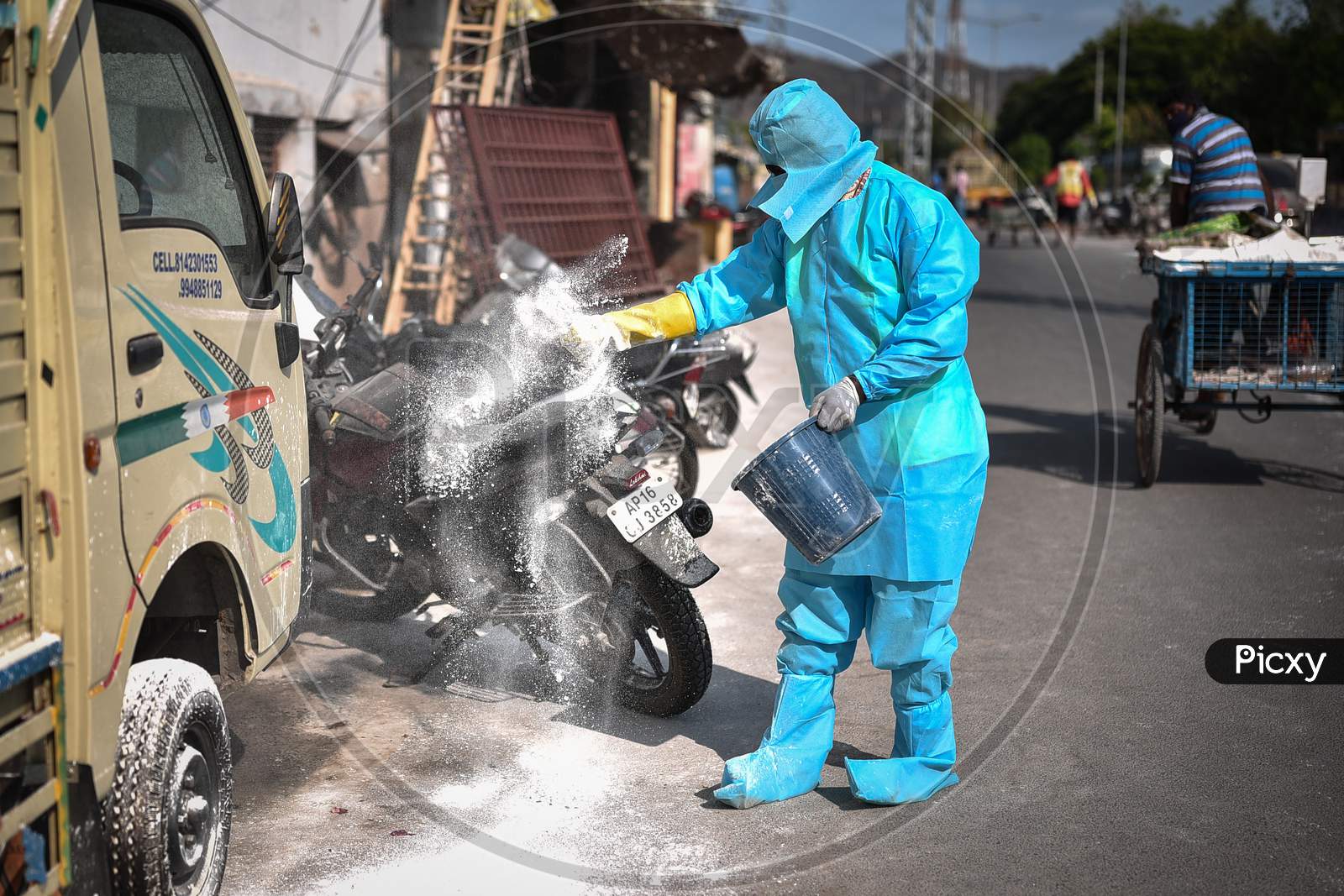 A Corporation Worker Wearing A Ppe Suit Throws Powdered Bleach At A Covid-19 Containment Area, During The Ongoing Coronavirus Lockdown, In Vijayawada.