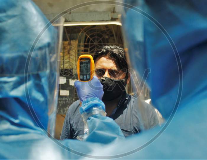 A doctor wearing protective suit scans residents from Dharavi, one of Asia's largest slums, with an infrared thermometer to check their temperature as a precautionary measure against the spread of the coronavirus disease (COVID-19), in Mumbai, India, April 12, 2020.