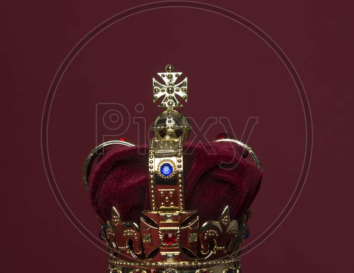 Golden Crown On A Velvet Cushion On A Deep Red Background With Copy Space In A Vertical Image