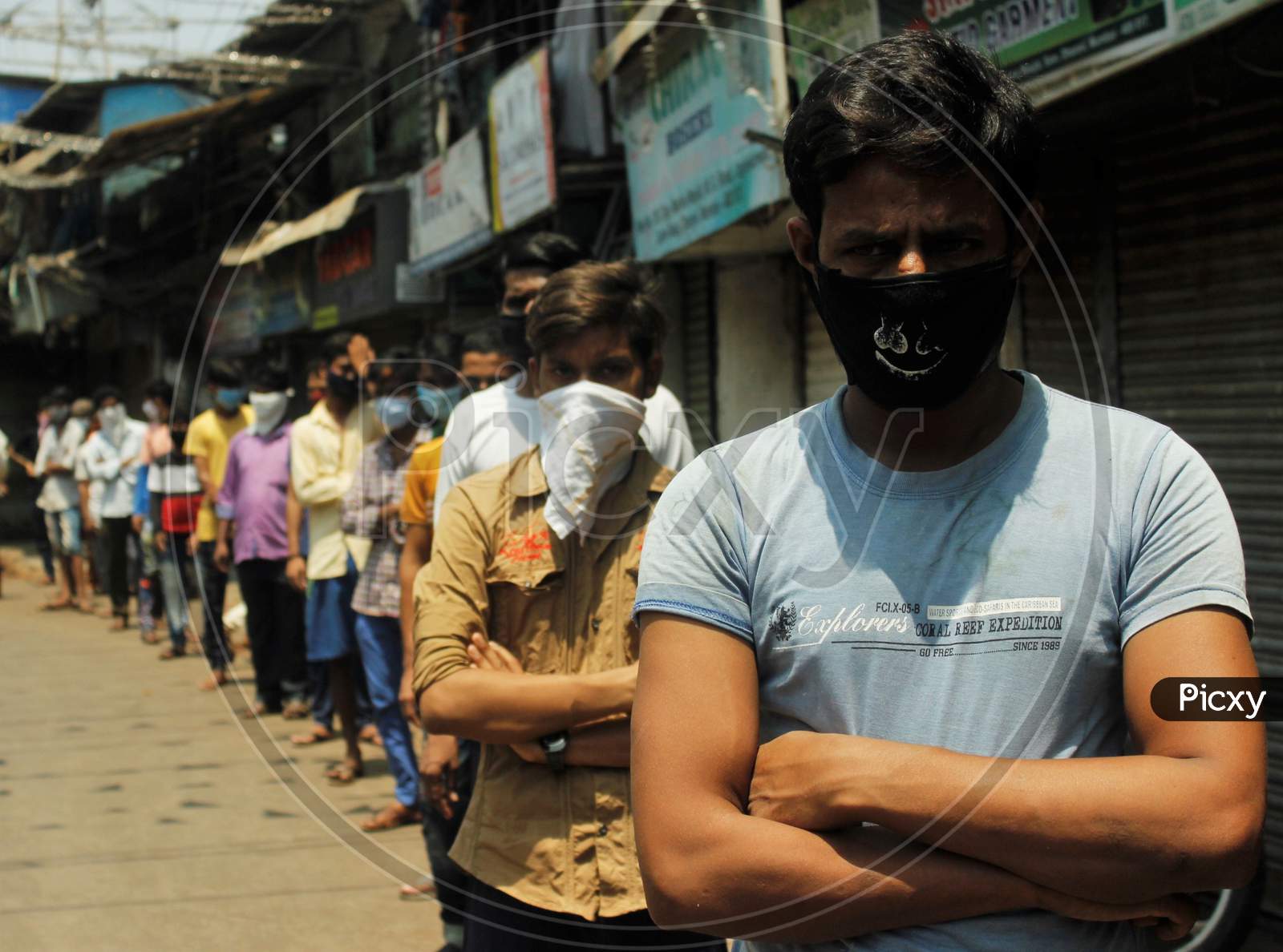 People wearing protective masks stand in a queue to collect food distributed by a masjid during a 21-day nationwide lockdown to limit the spreading of coronavirus disease (COVID-19)  at a slum in Dharavi(one of Asia's largest slum), in Mumbai, India on April 12, 2020.