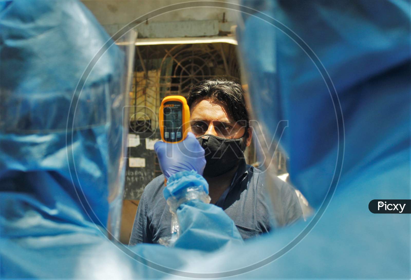A doctor wearing protective suit scans residents from Dharavi, one of Asia's largest slums, with an infrared thermometer to check their temperature as a precautionary measure against the spread of the coronavirus disease (COVID-19), in Mumbai, India, April 12, 2020.