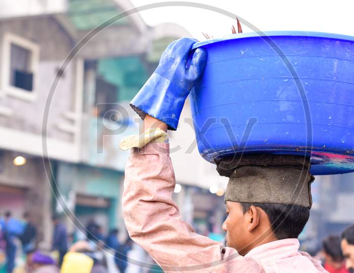 Delhi 2019 : A daily wager carrying blue color plastic tub on his head. Daily wagers provide their services in fish market on routine basis