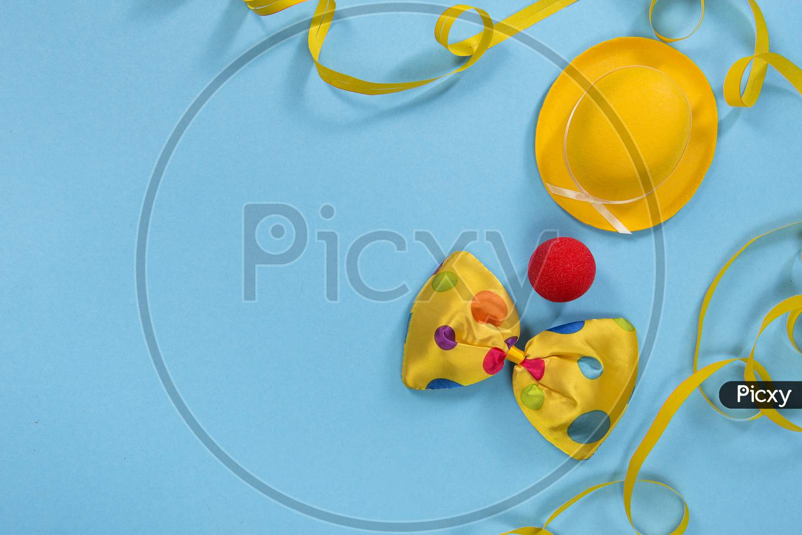 Party Flatlay With Garland, Hat, Nose And A Bow Of A Clown On A Blue Background With Space For Copy