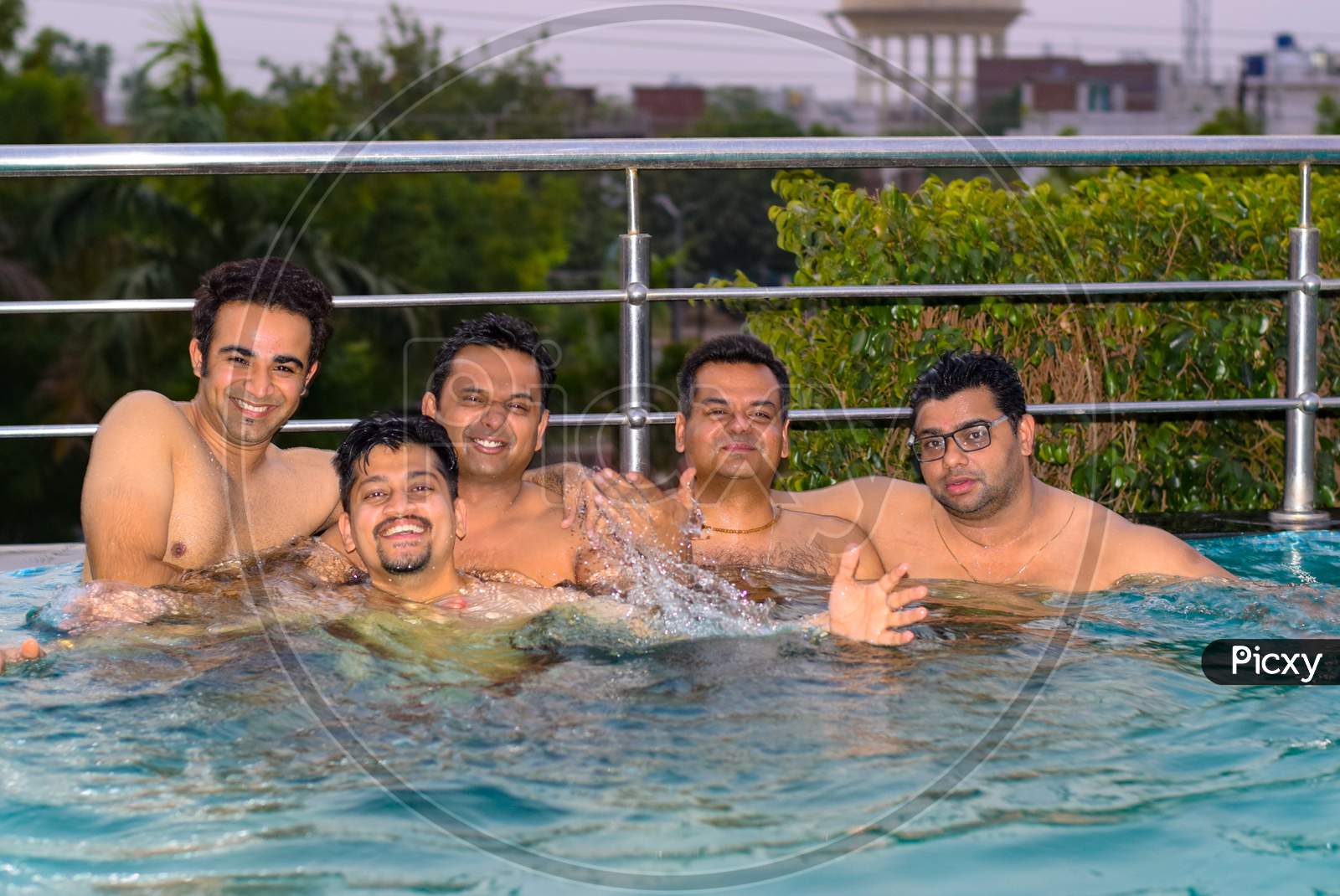 Delhi, 2018 : Group of boys playing and enjoying in swimming pool during summers. The swimming pool is surrounded by steel grill