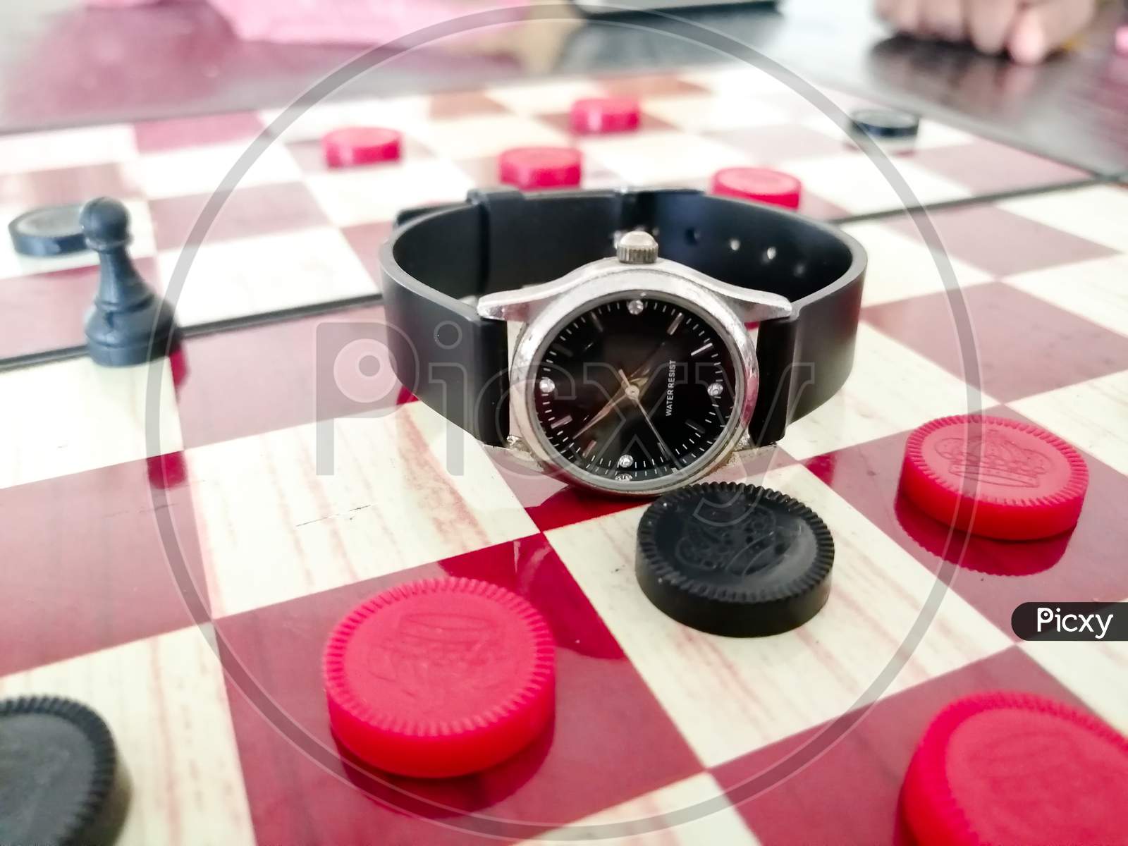 There Is A Ladies Wrist Watch On The Chess Board.
