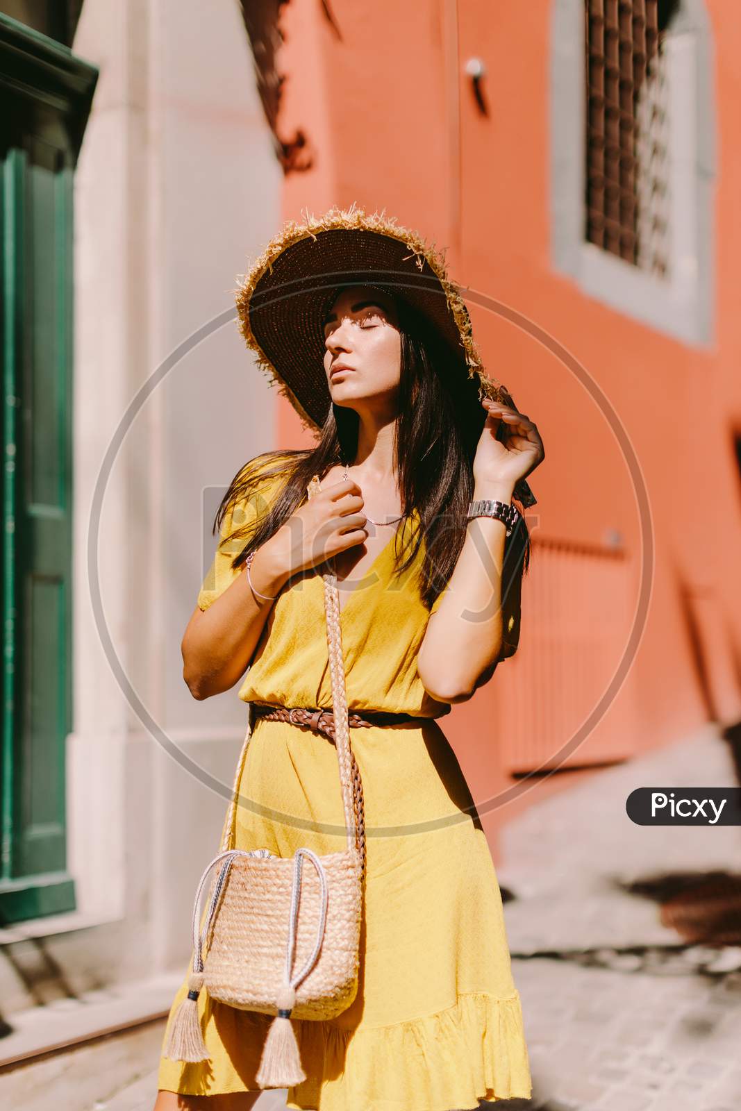 Attractive Woman In Summer Dress And Straw Hat With Handbag Walking