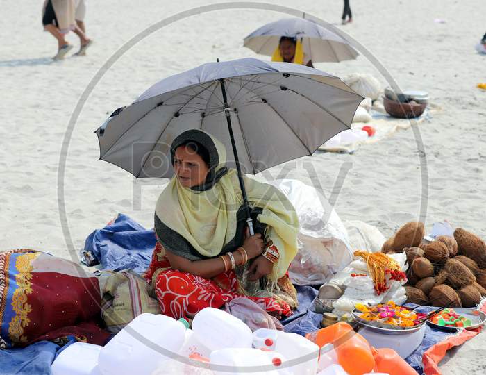 A Woman Taking Shield From Umbrella On a Hot Summer Day At The River Bank Of Ganga In Prayagraj on May 31, 2020