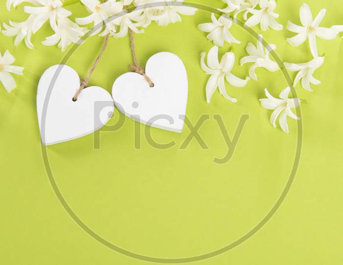 White Wooden Hearts With White Flowers On A Green Background With Space For Copy