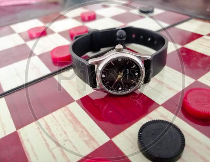 There Is A Ladies Wrist Watch On The Chess Board.