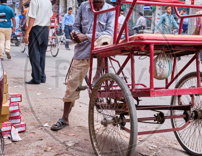 Poor Rickshaw Driver With His Bicycle Rickshaw At Chandni Chowk, A Busy Shopping Area In Old Delhi With Bazaars And Colorful Narrow Streets