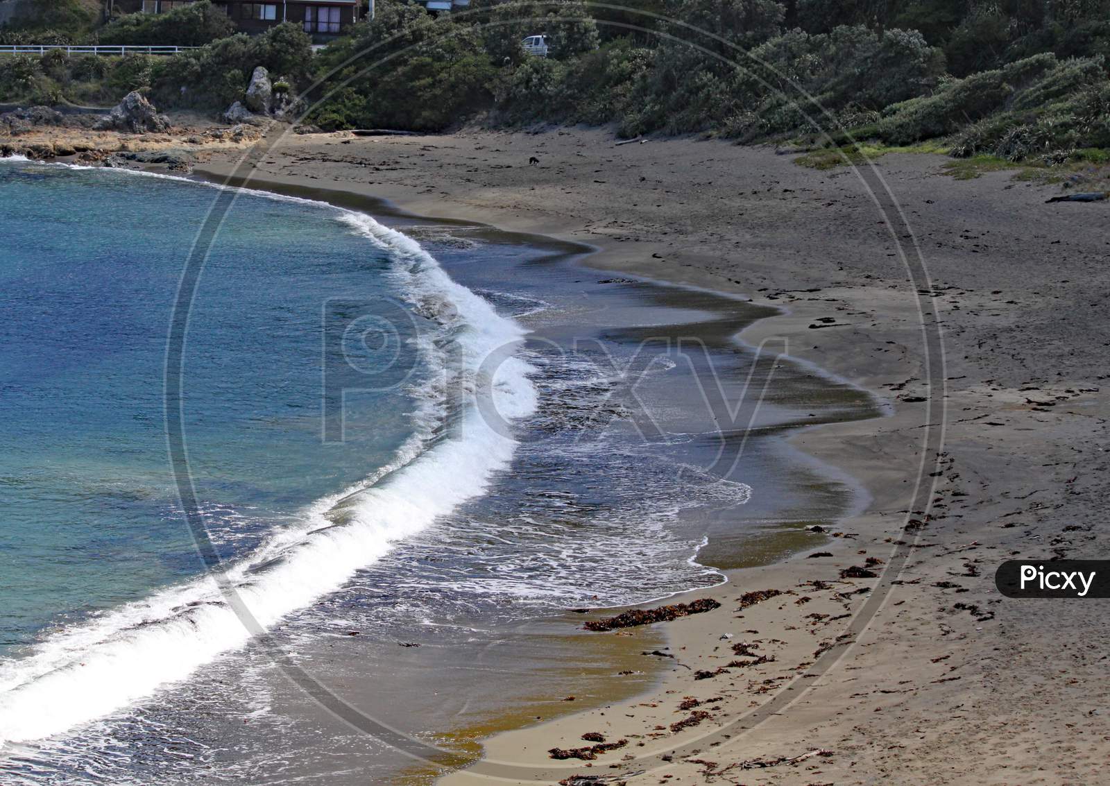 A Quiet Bay With Waves Gently Washing On To The Beach Near Wellington, New Zealand