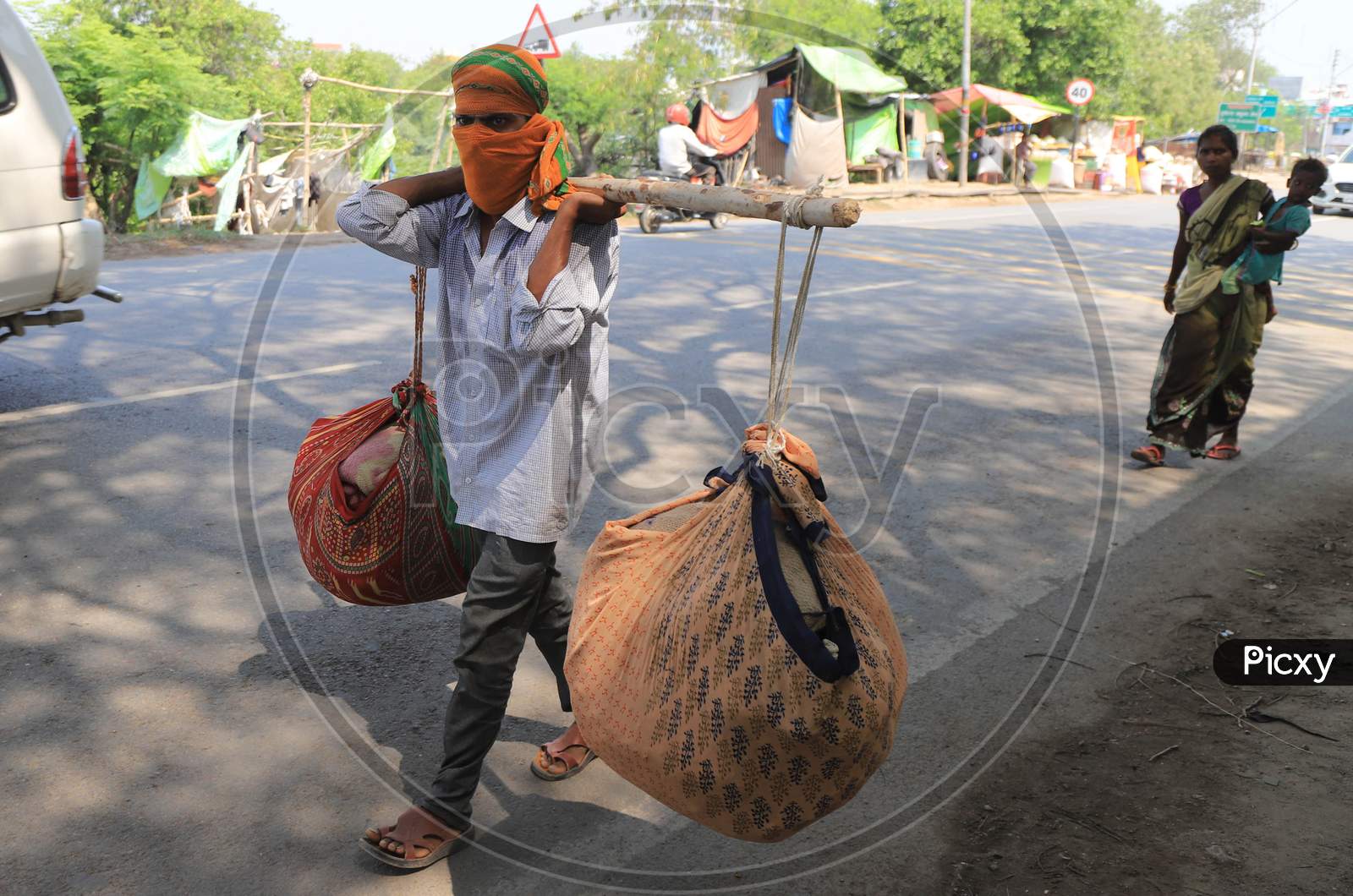 A migrant laborer carrying goods walks on the road during an extended nationwide lockdown to slow the spread of the Coronavirus disease, in Prayagraj, May 4, 2020.