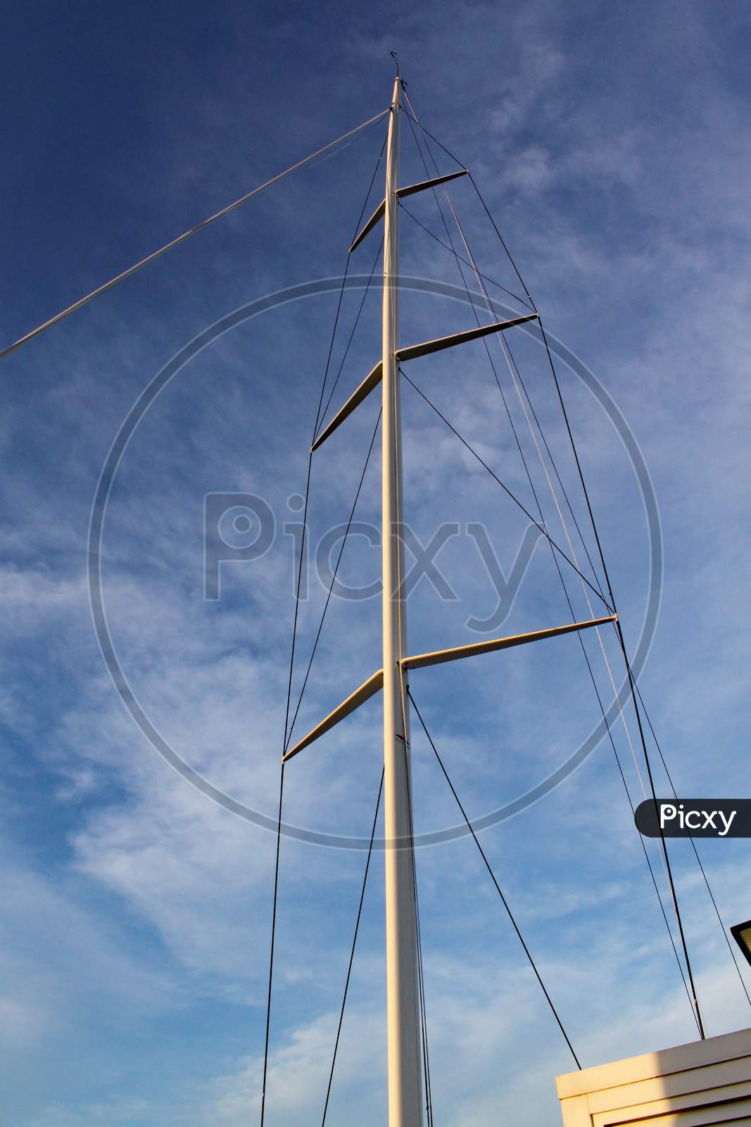 The Mast And Rigging Of A Racing Yacht Stands Out Against The Clear Blue Sky.