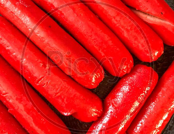 Filipino hotdog sausages cooking in a frying pan