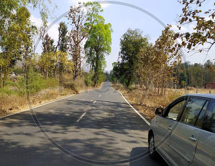 Empty Road in forest and car parked in corner