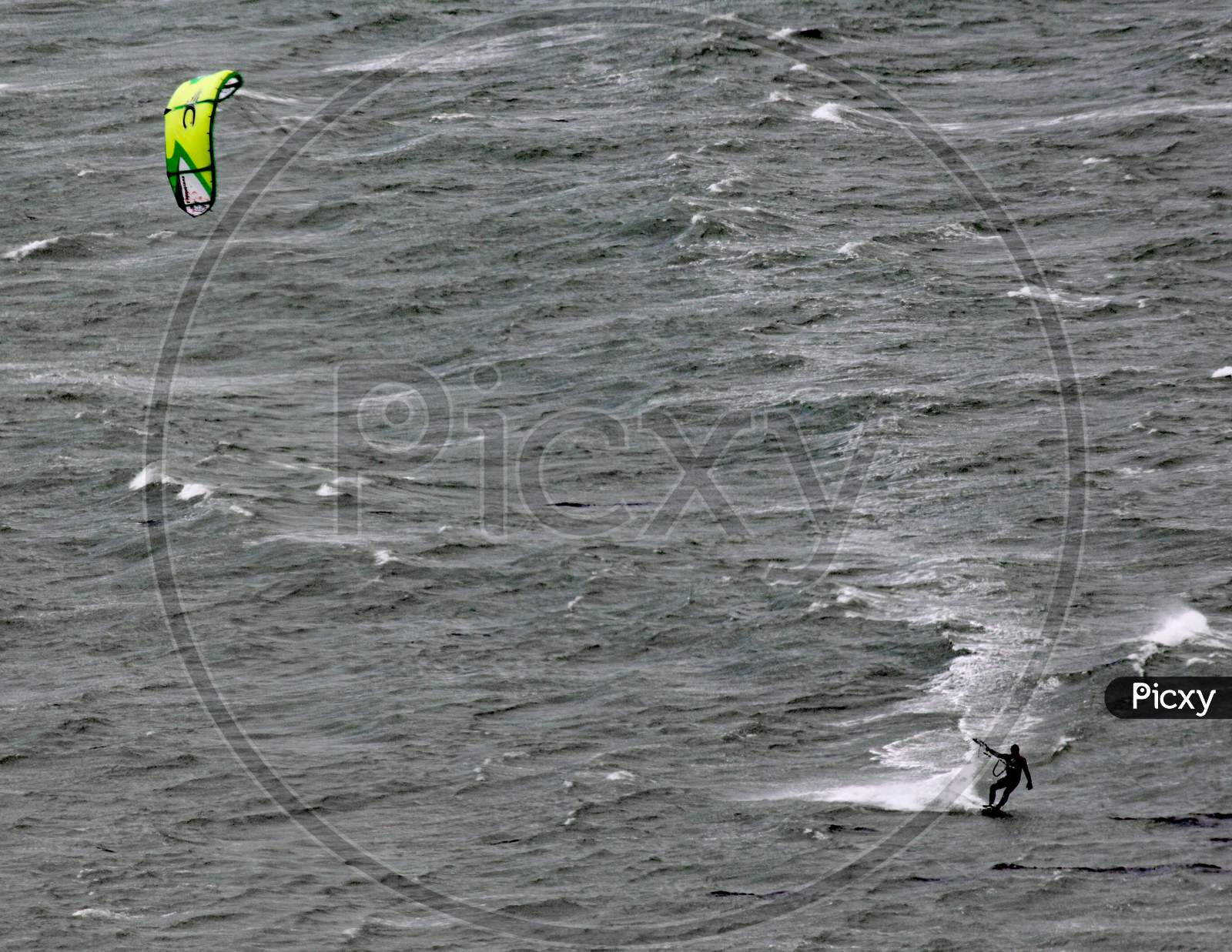 A Kite Surfer Moves Across Lyall Bay In Wellington New Zealand On A Grey Stormy Day