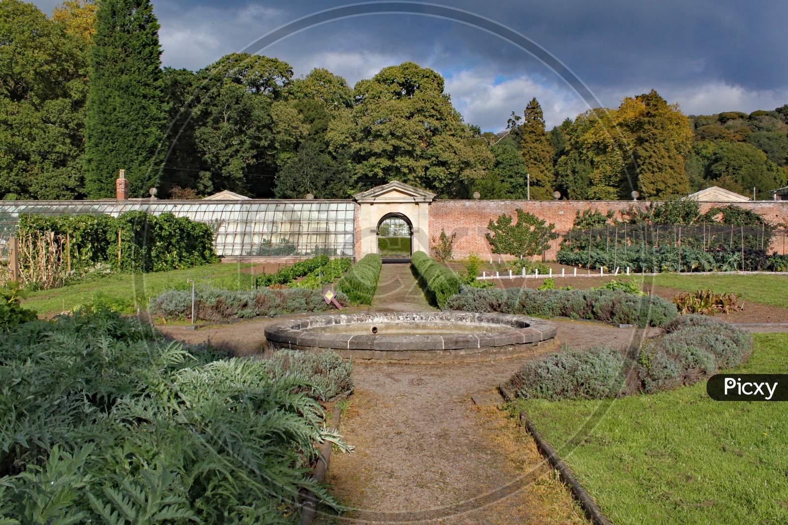 Walled Kitchen Garden With A Pathway And A Circular Fountain.