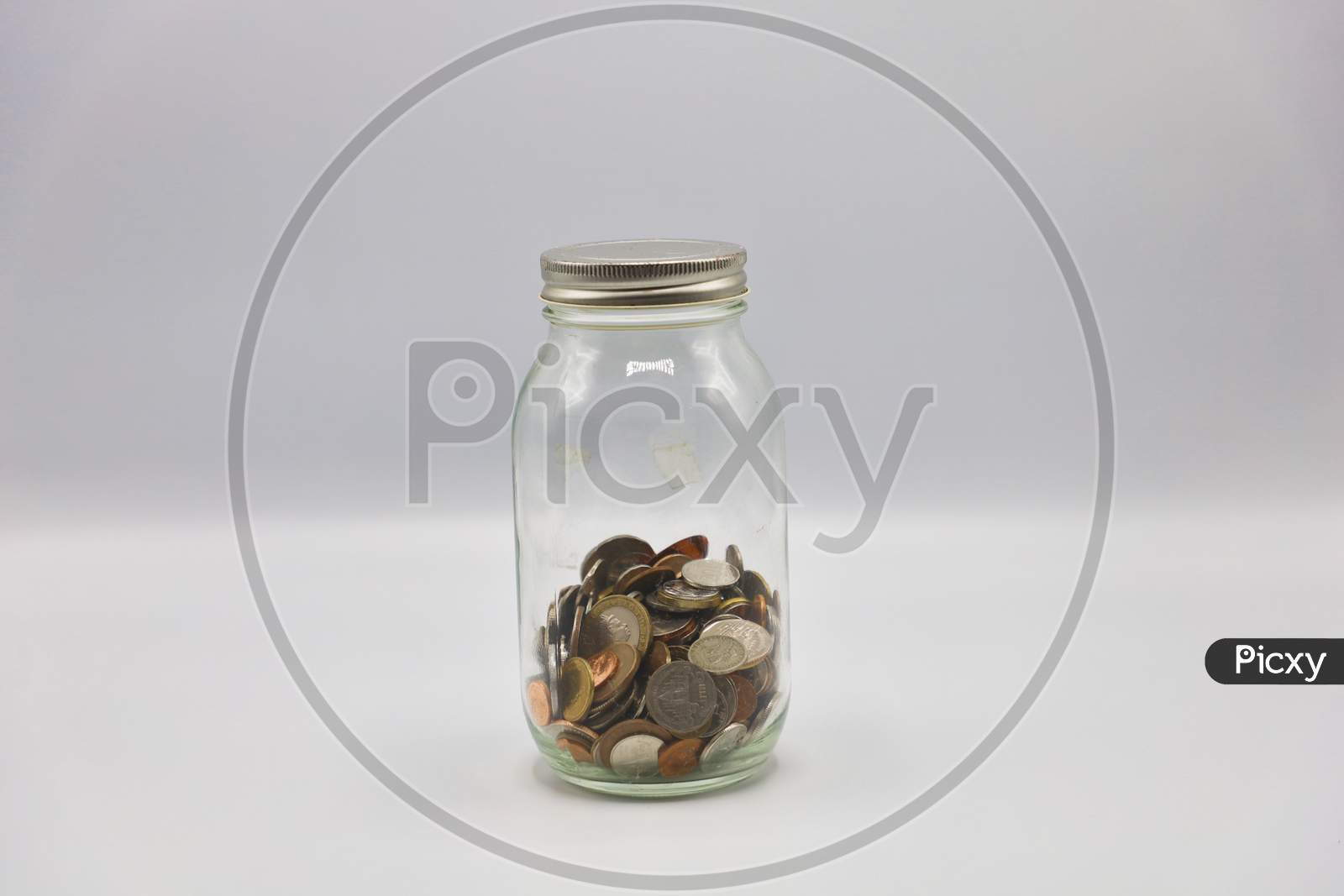 Currency Coins in a Transparent Glass Bottle Isolated with White Background
