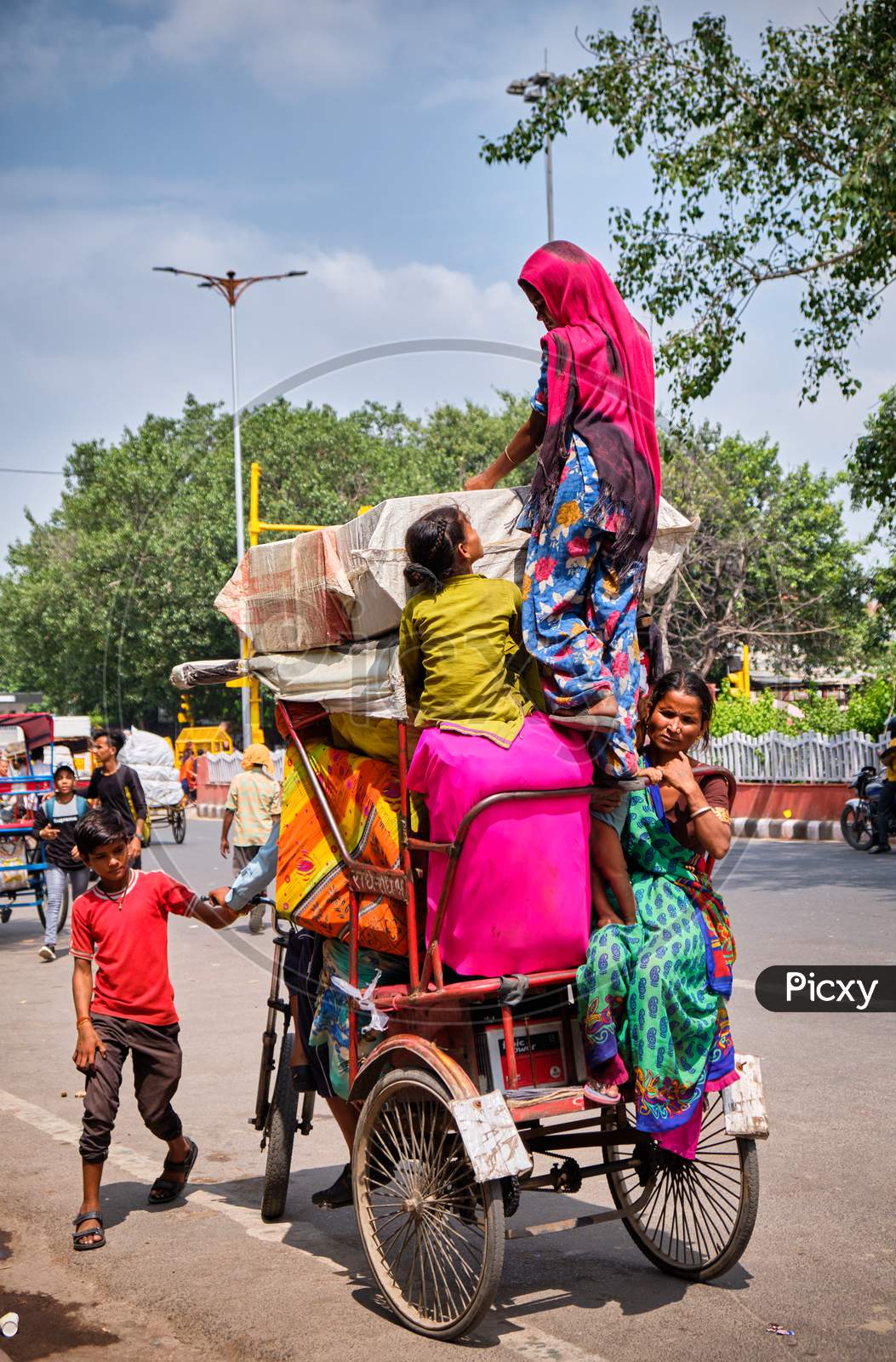 Family Of Several People Climbing On A Bicycle Rickshaw In New Delhi, India