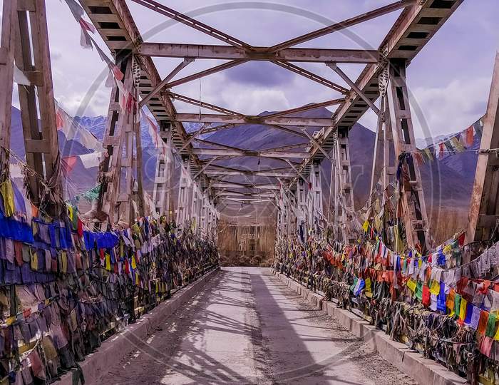Colourful Buddhist prayer flags on a bridge above Indus river in the Himalayan mountain, Leh, Ladakh, India