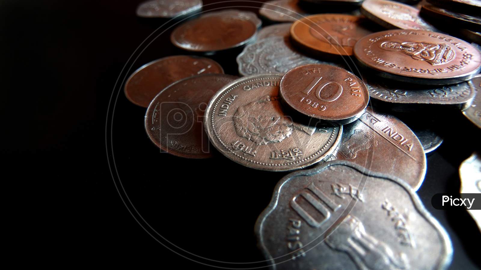 Closeup  shot of coins displaying Indian currency of various values on a dark background