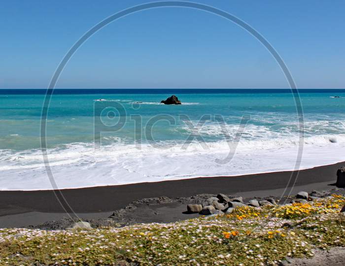 Waves And Foam Wash Up On To The Deserted Beach At Cape Palliser, North Island, New Zealand