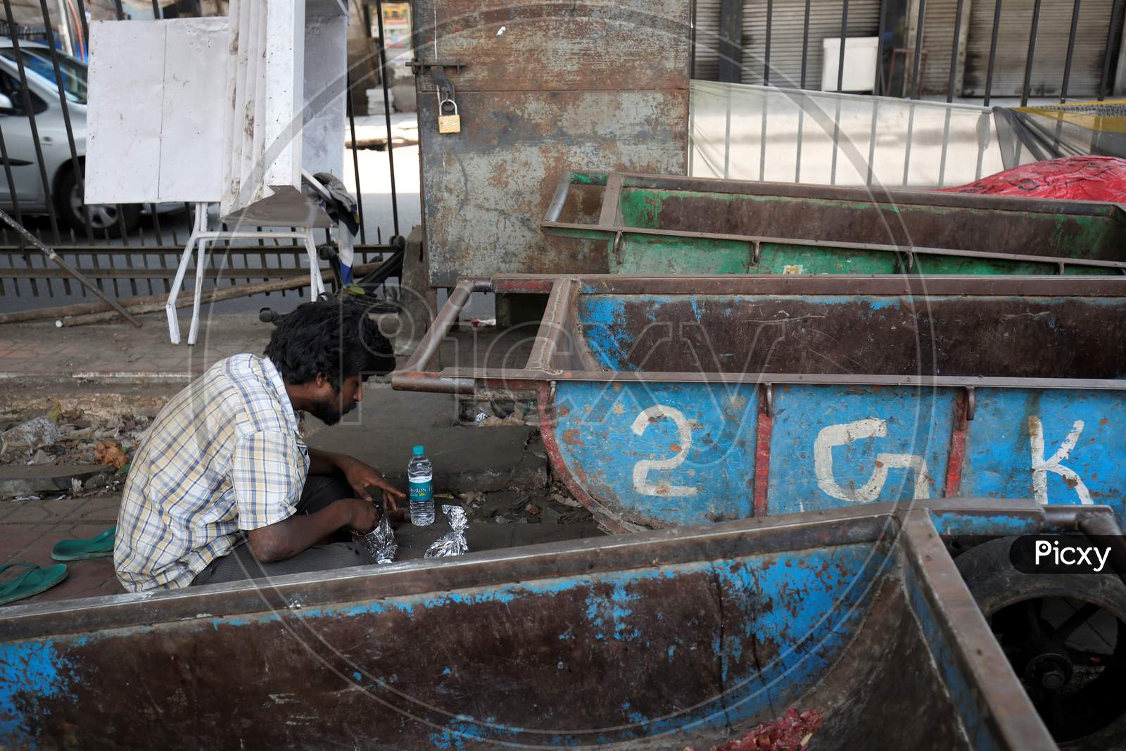 A homeless man eats his food next to pushcarts in a market during the nationwide lockdown to stop the spread of Coronavirus (COVID-19) in Bangalore, India, May 01, 2020.