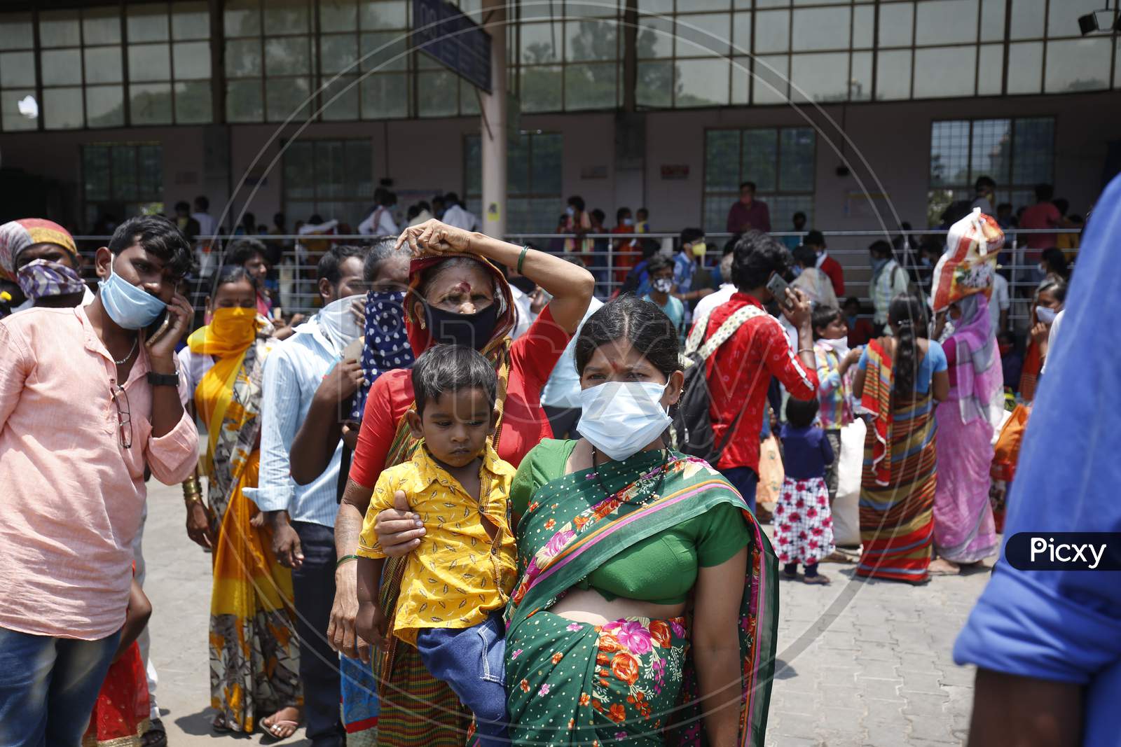 A woman carries a baby as she waits for a bus at a bus station during the nationwide lockdown to stop the spread of Coronavirus (COVID-19) in Bangalore, India, May 02, 2020.