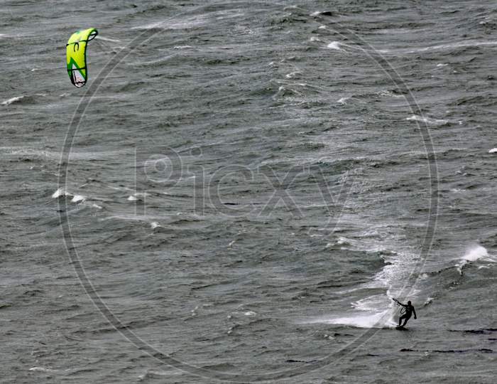 A Kite Surfer Moves Across Lyall Bay In Wellington New Zealand On A Grey Stormy Day
