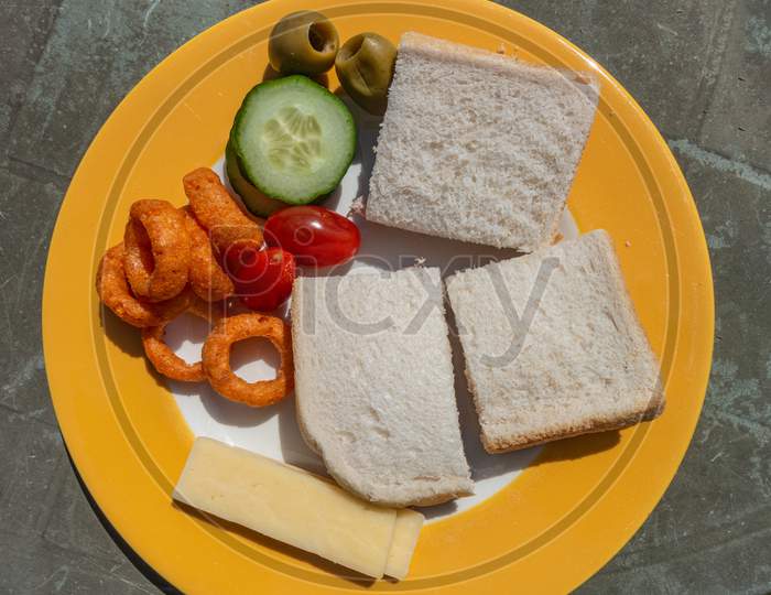 A plate of food comprising of sandwiches and salad vegetables on an old garden table.