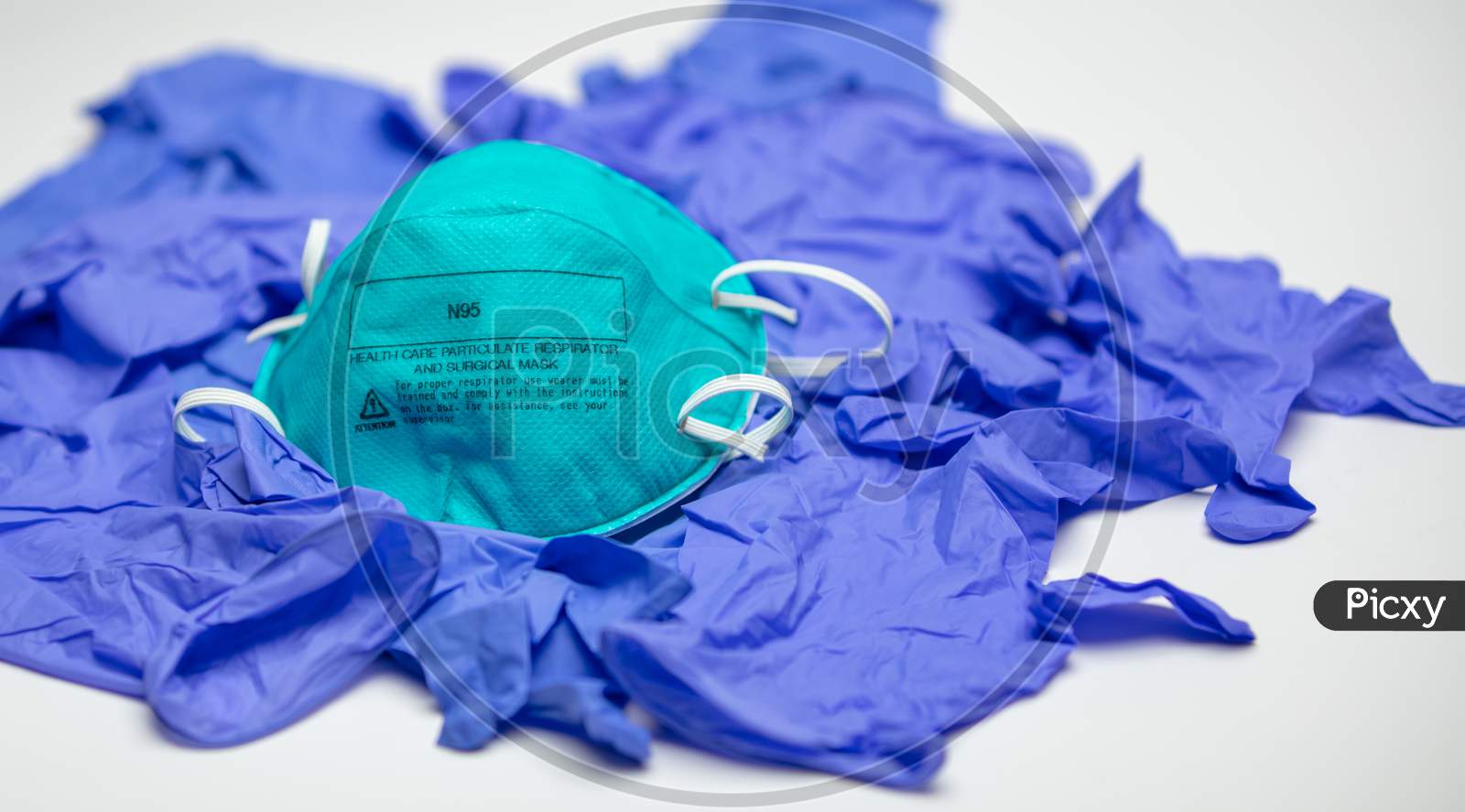 A Turquoise N95 Particulate Respirator And Surgical Mask On Top Of Many Medical Gloves.