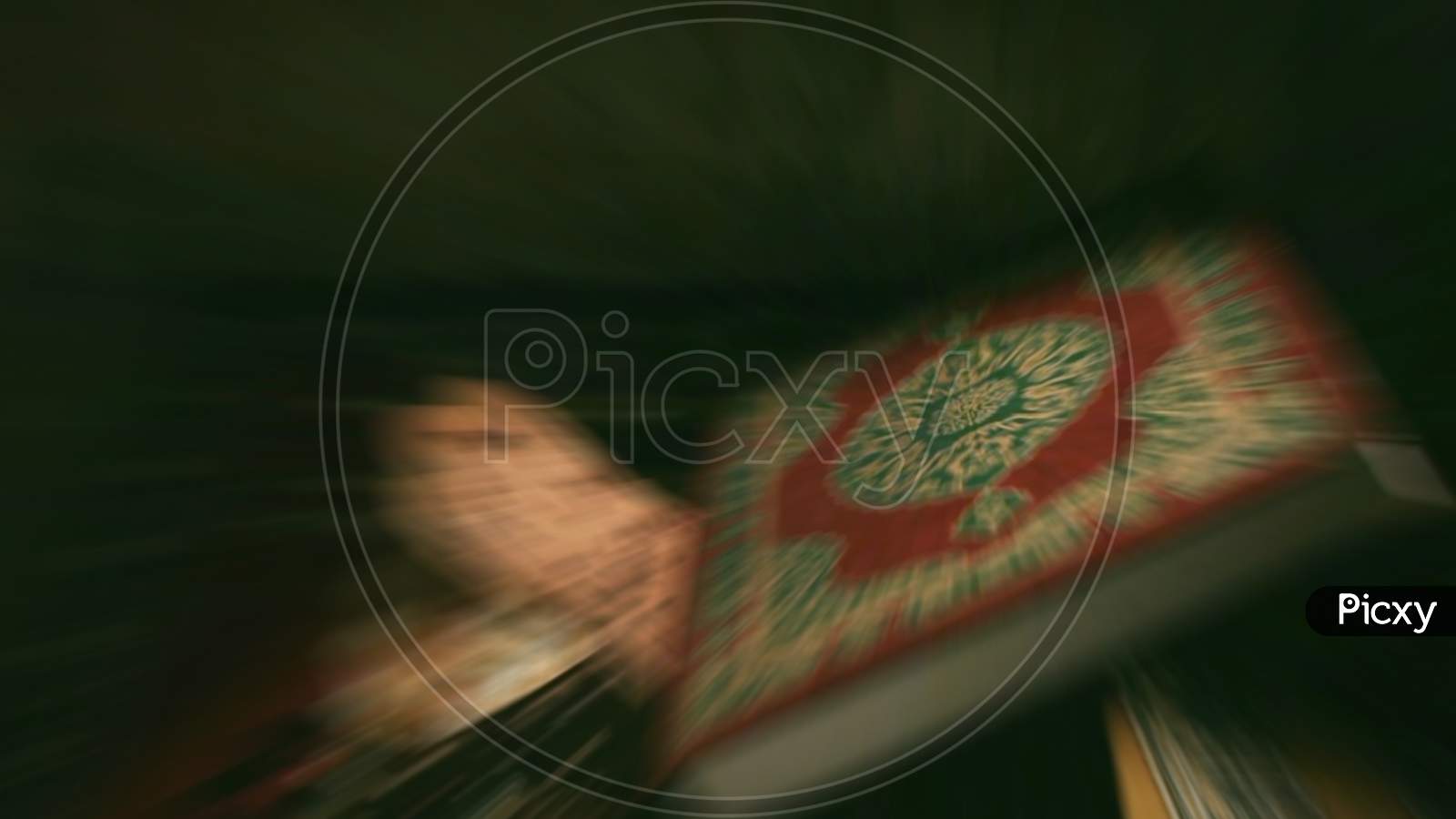 Blurred Shot Of Quran Book Cover With Arabic Calligraphy That Means Al-Quran, The Holy Quran.Ramadhan Kareem/Eid Fitr Concept.