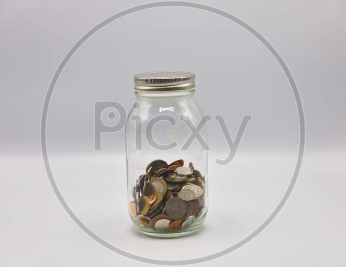 Currency Coins in a Transparent Glass Bottle Isolated with White Background