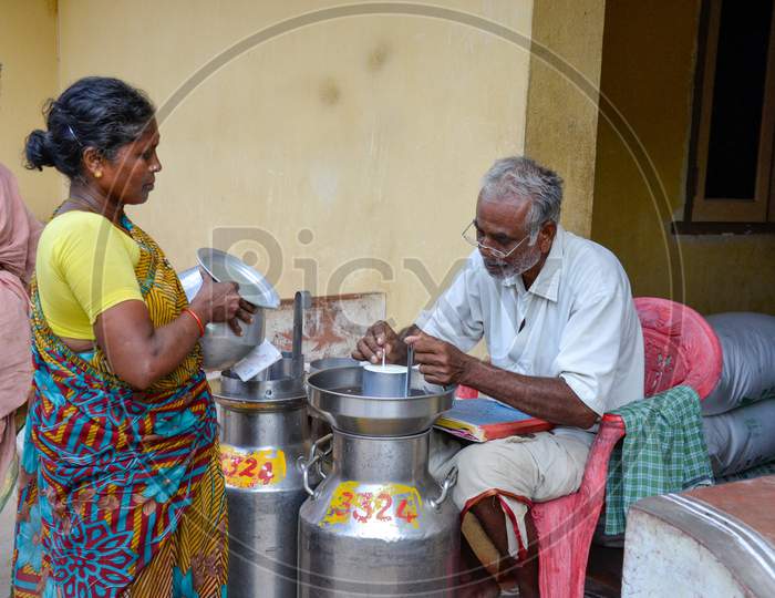INDIA, ANDHRA PRADESH, TIRUPATI -  JUNE 2019, Rural woman in southern India pouring milk at a milk pooling point, while the collection supervisor records the quantity of the milk & do the testing.