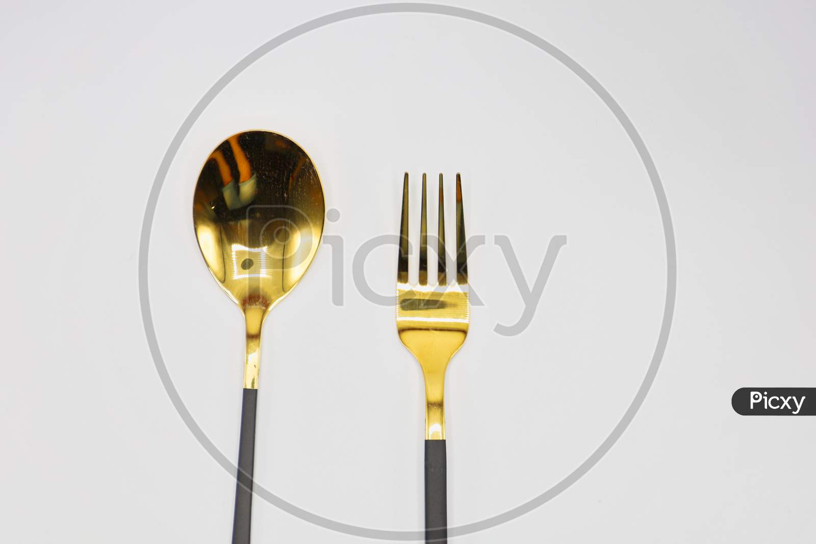A golden-colored spoon and fork in a white sheet.