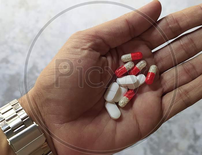 Tablets and capsules in hand close up shot