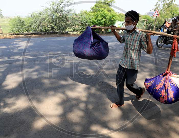 A migrant laborer carrying goods walks on the road during an extended nationwide lockdown to slow the spread of the coronavirus disease, in Prayagraj, May 4, 2020.