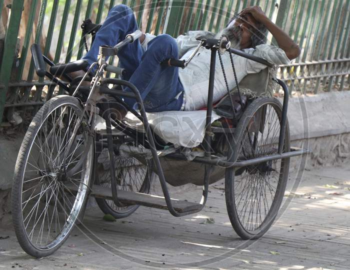 DELHI INDIA, APRIL 2019, A handicapped disabled man beggar sleeping in his hand driven rickshaw wheel chair in afternoon
