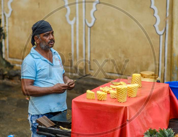 Indian Man Sells Freshly Carved Pineapples On Street Food Fruit Stall In Jaipur, India