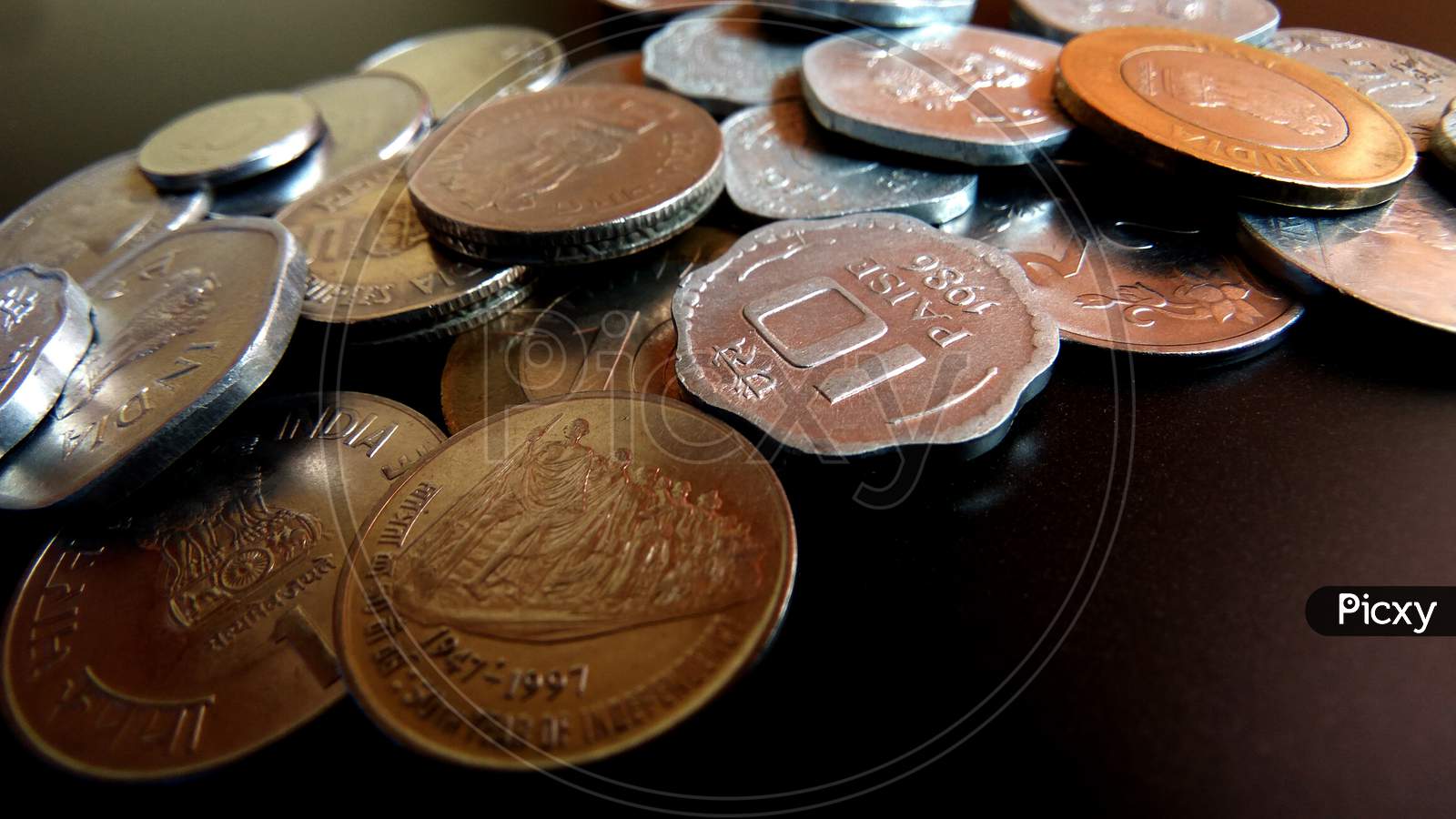 Closeup shot of coins displaying Indian currency of various values on a dark background