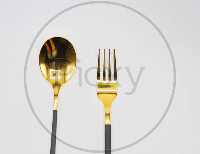 A golden-colored spoon and fork in a white sheet.