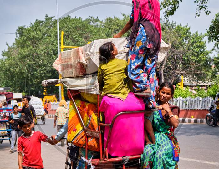 Family Of Several People Climbing On A Bicycle Rickshaw In New Delhi, India