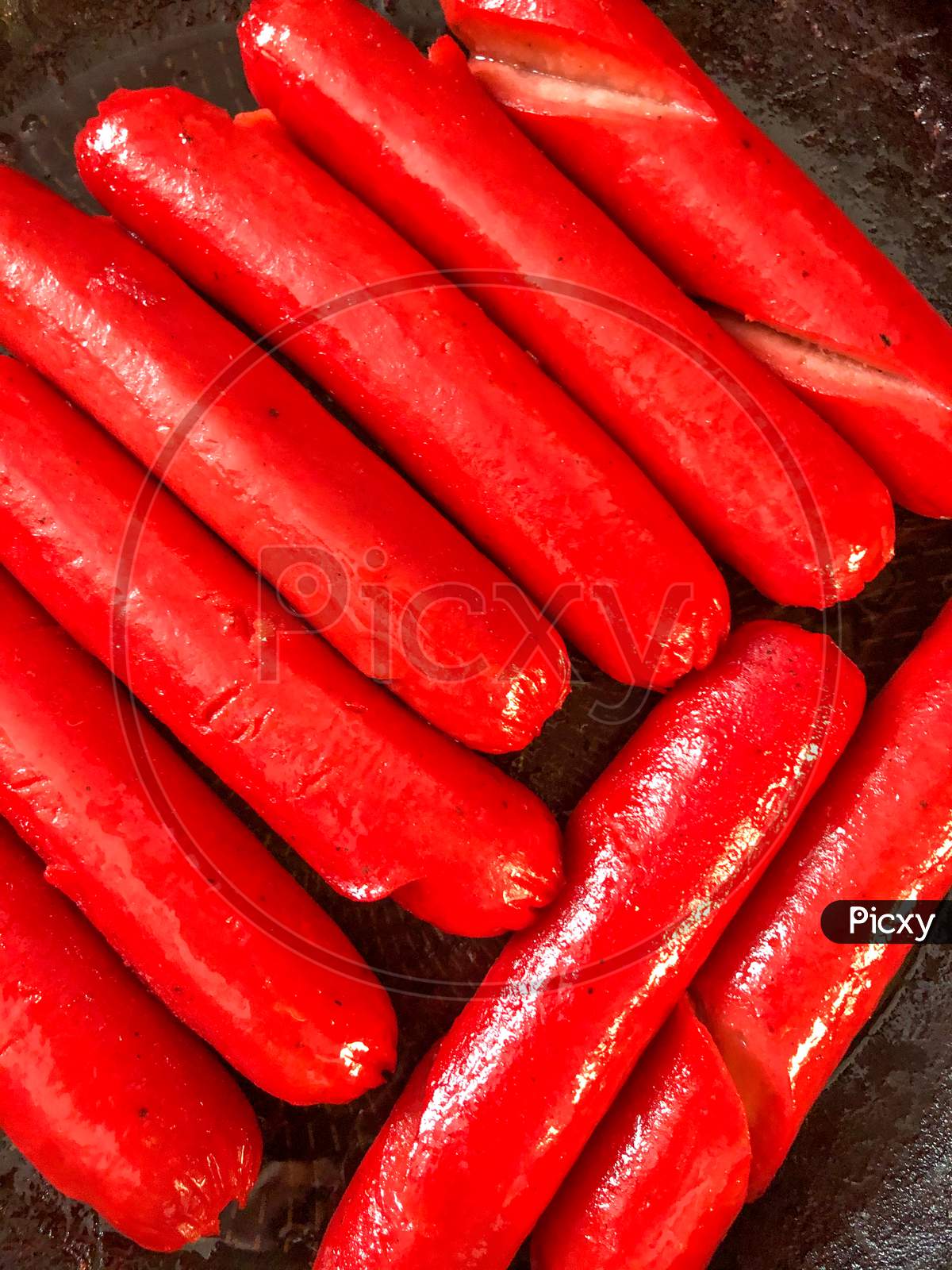 Filipino hotdog sausages cooking in a frying pan